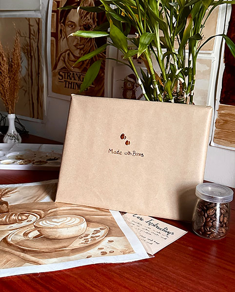 A finished painting and a wrapped commission package on a desk, with a plant in the background