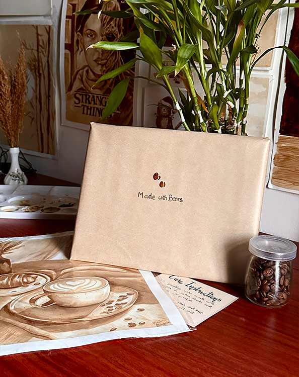 A finished commission carefully packaged with kraft paper, sitting beside coffee beans and a finished painting